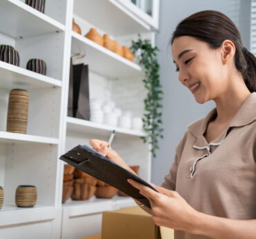 Asian beautiful woman check vase goods order for customer from shelf. Young attractive business girl working to preparing parcel boxes checking ecommerce shipping online retail to sell at home store.