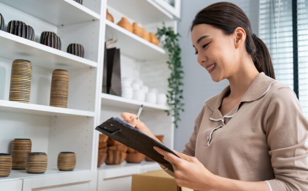 Asian beautiful woman check vase goods order for customer from shelf. Young attractive business girl working to preparing parcel boxes checking ecommerce shipping online retail to sell at home store.