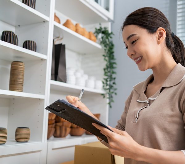Asian beautiful woman check vase goods order for customer from shelf. Young attractive business girl working to preparing parcel boxes checking ecommerce shipping online retail to sell at home store.