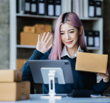 Asian fashion video blogger selling empty boxes online with smartphones.