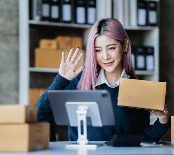 Asian fashion video blogger selling empty boxes online with smartphones.
