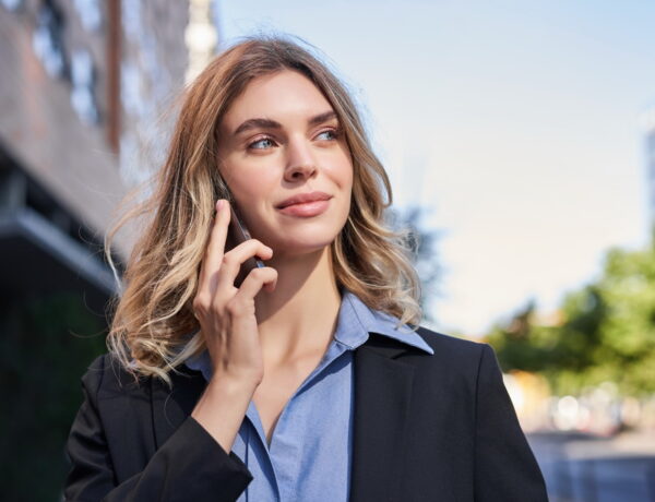 Close up portrait of smiling saleswoman, successful female manager having phone call, answer telephone and walking on street.