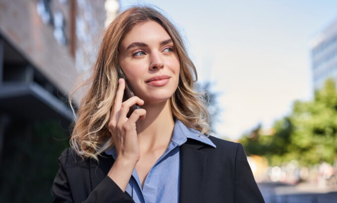 Close up portrait of smiling saleswoman, successful female manager having phone call, answer telephone and walking on street.